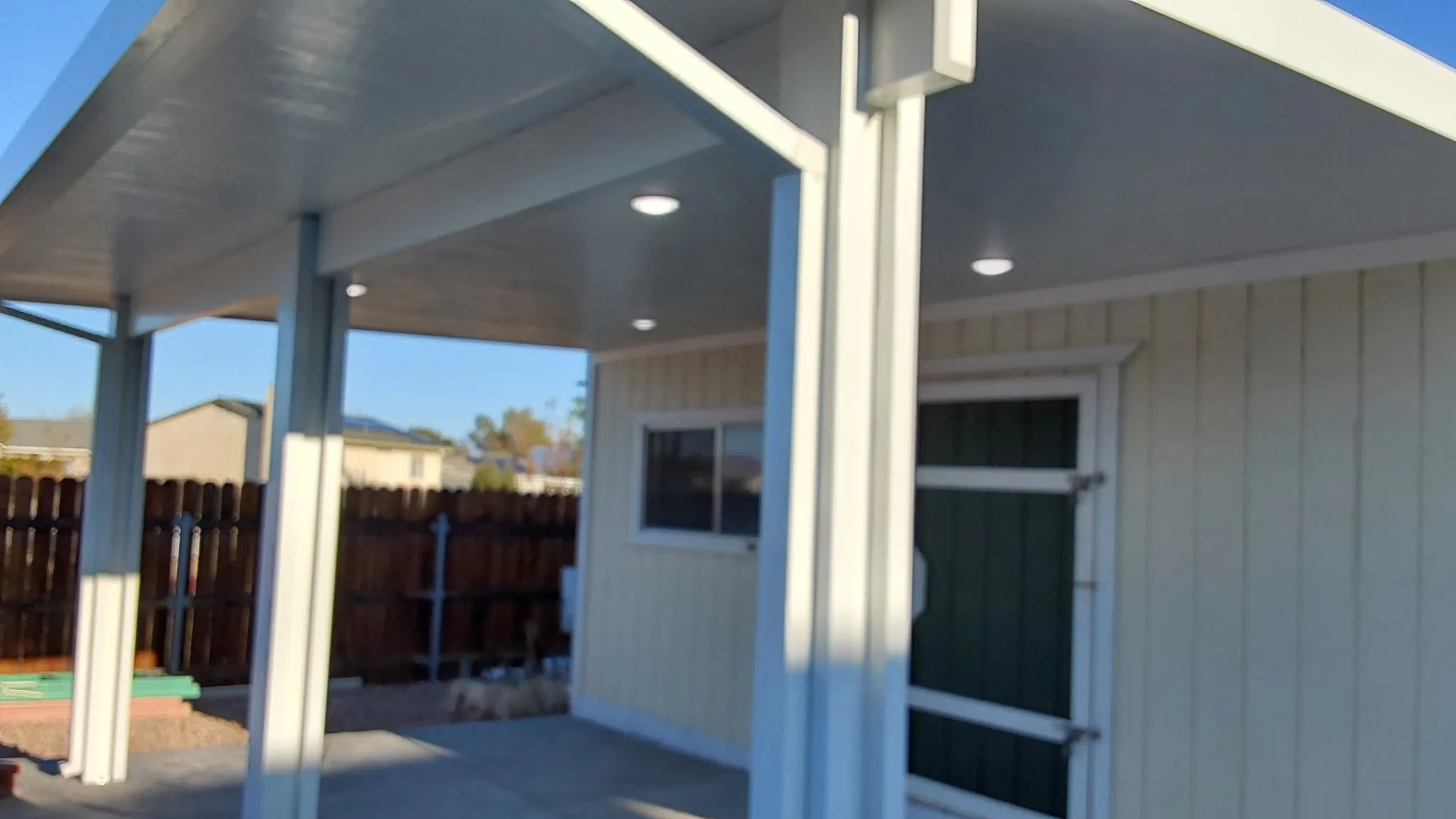 New aluminum patio cover with recessed lighting alongside a pool house