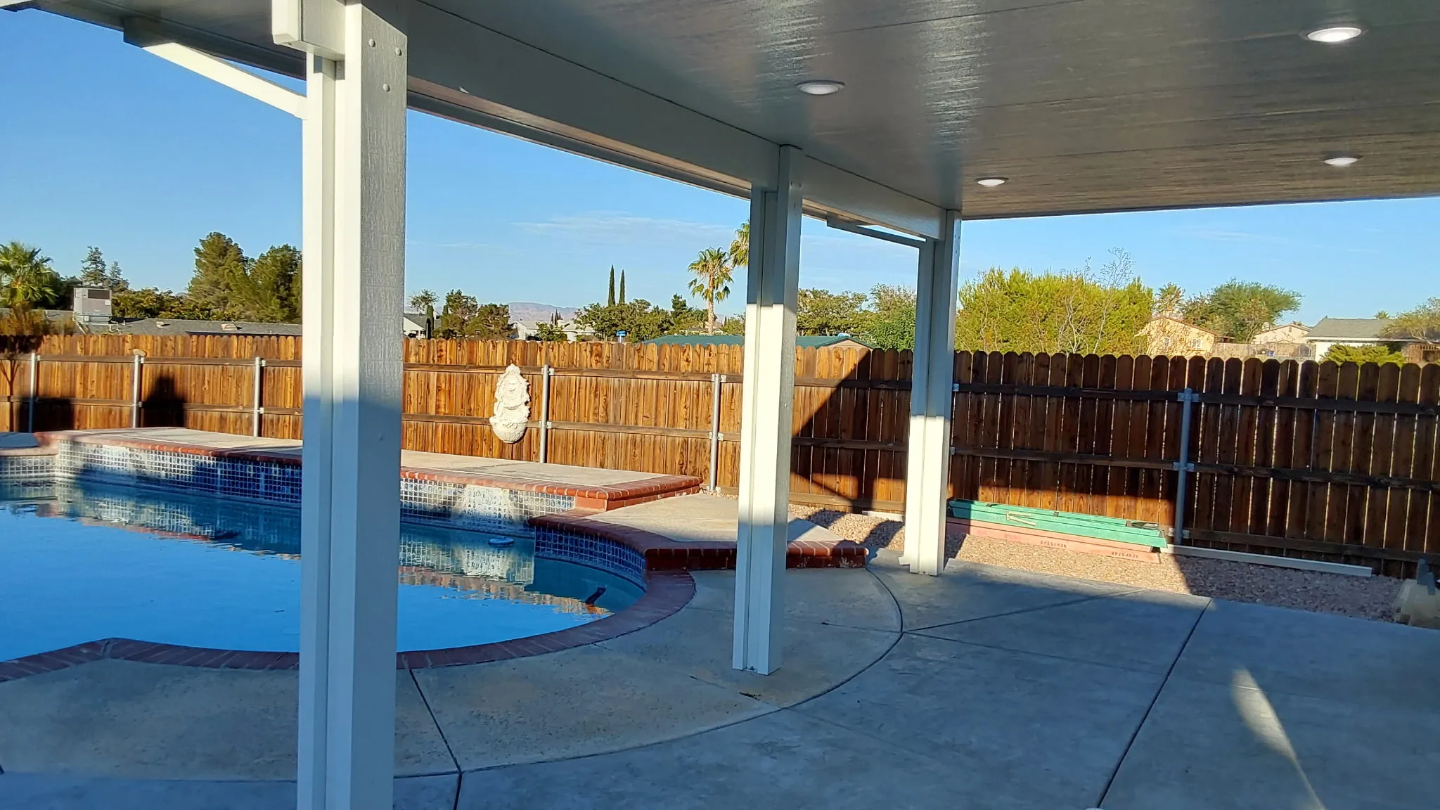 Poolside view of a new aluminum patio cover with recessed lighting
