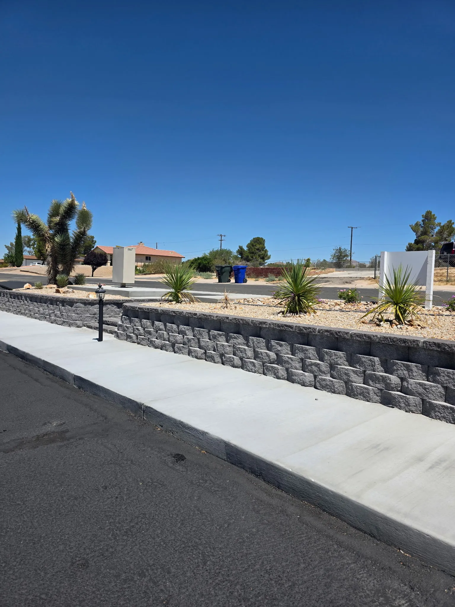 Retaining wall and paver walkway on a corner lot, planted with yucca and accent rock