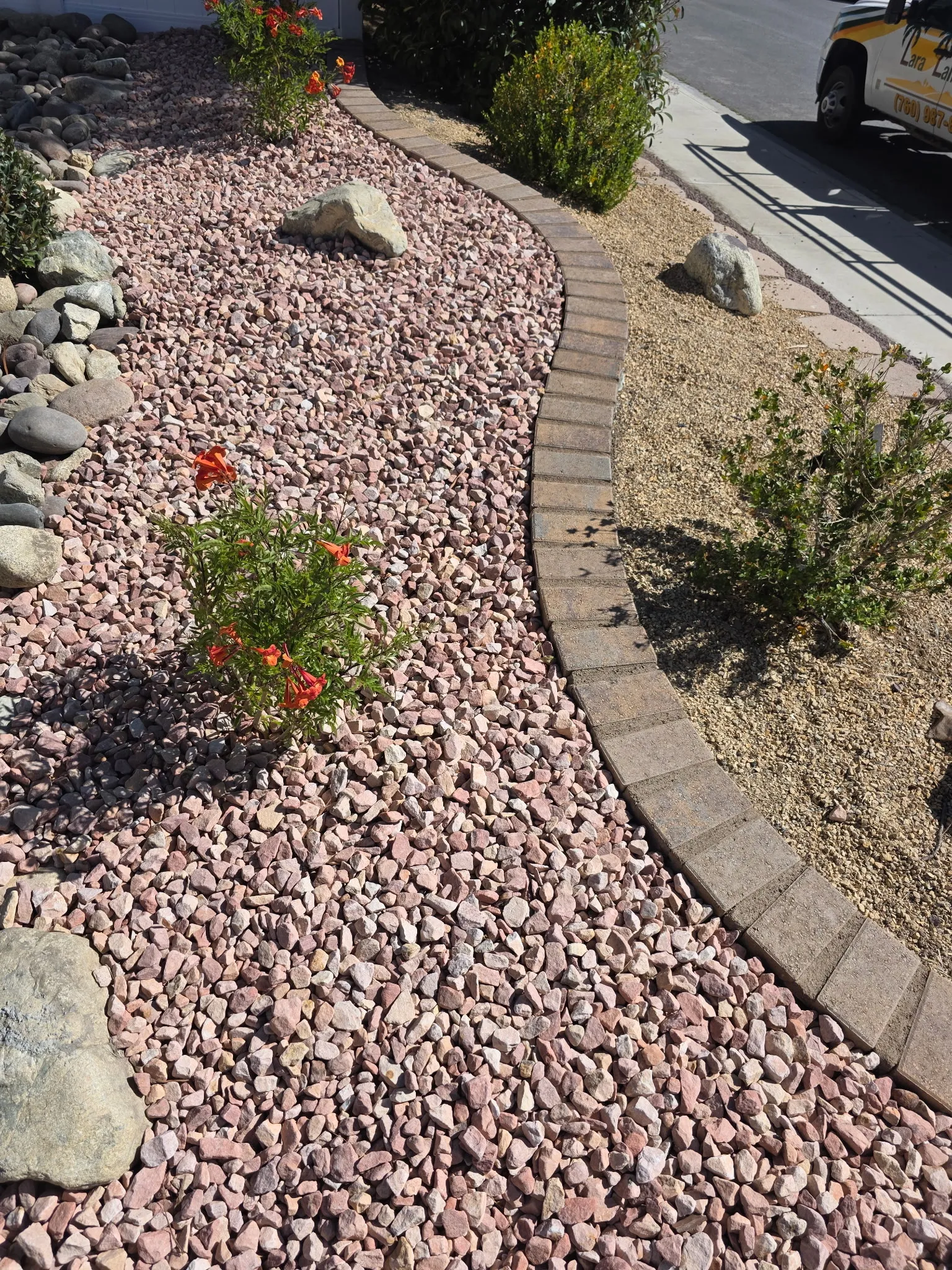Curved rockscape bed with contrasting stone and block edging