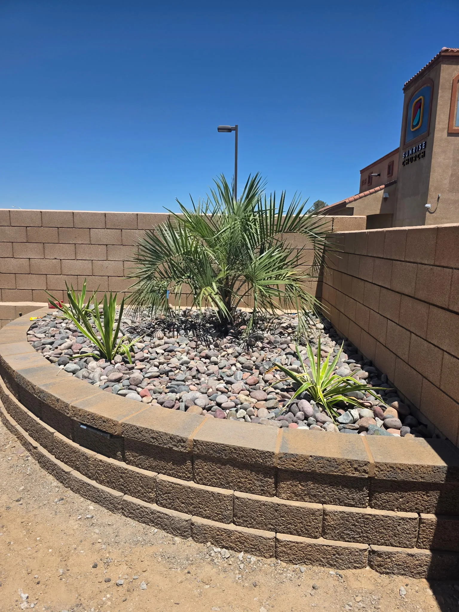 Curved raised planter built with retaining-wall block and river rock