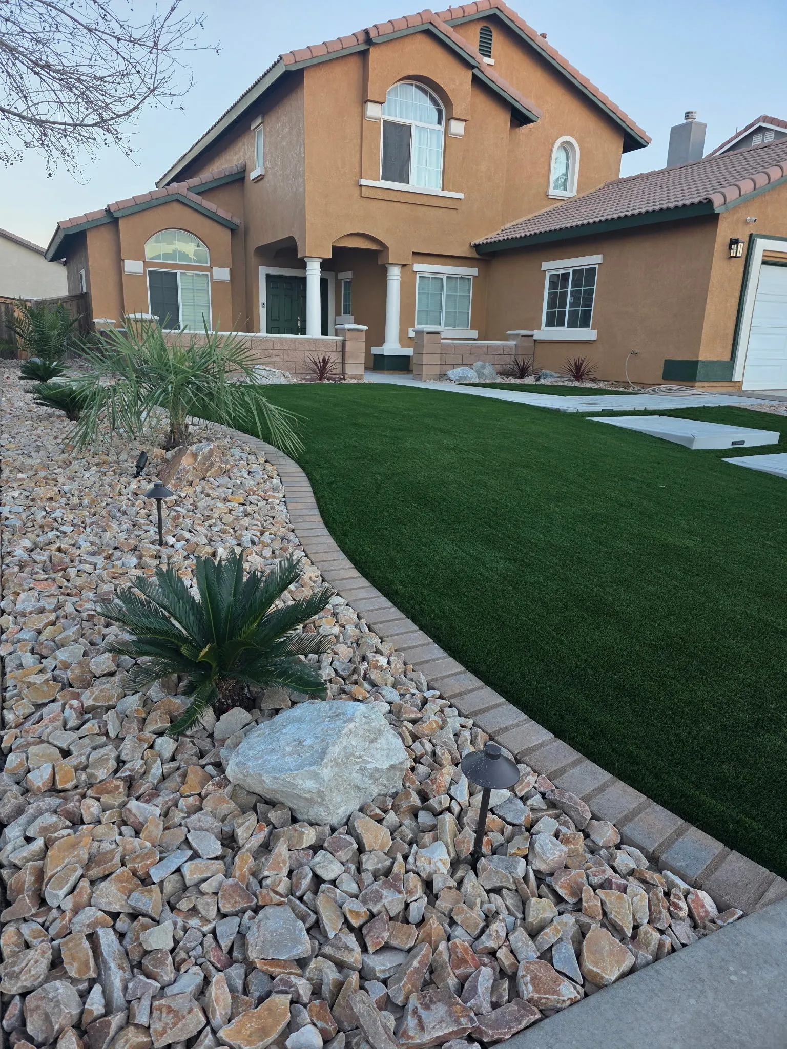Finished front yard with artificial grass, desert plants, and decorative rock
